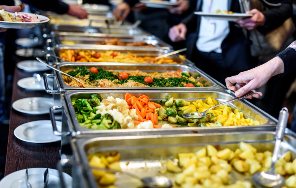 A buffet line with various silver chafing dishes filled with food