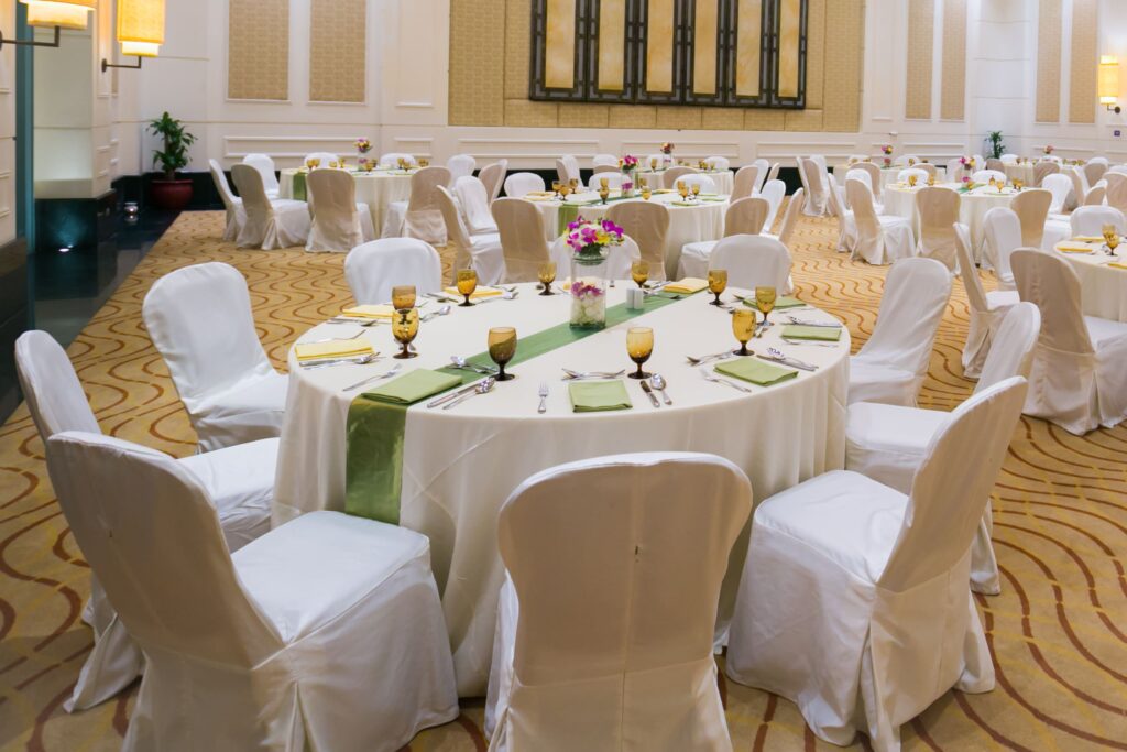 An elegant banquet hall featuring round tables set with white tablecloths